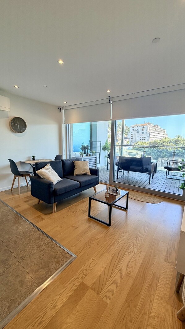 A modern living room with a sofa, coffee table, and dining area. - Gibraltar Luxury w/ Rooftop Pools & Views (Gibraltar)