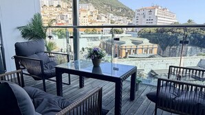 Ein Balkon mit einem Glastisch, zwei Korbschaukeln und einem Blumentopf.