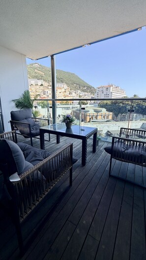 Ein Balkon mit einem Glastisch, zwei Korbschaukeln und einem Blumentopf.