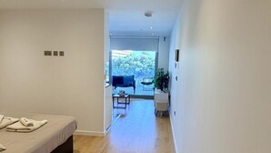 Ein modernes Interieur mit Holzboden, einem Bett, einem kleinen Tisch und Blick auf eine Terrasse.