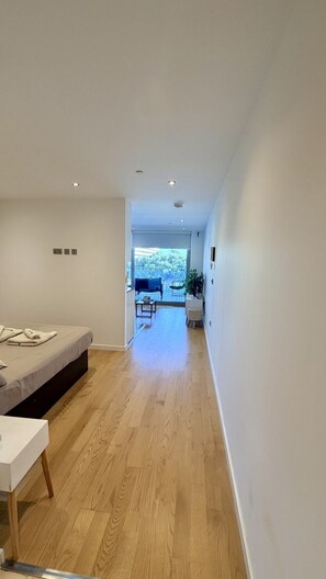 Ein modernes Interieur mit Holzboden, einem Bett, einem kleinen Tisch und Blick auf eine Terrasse.