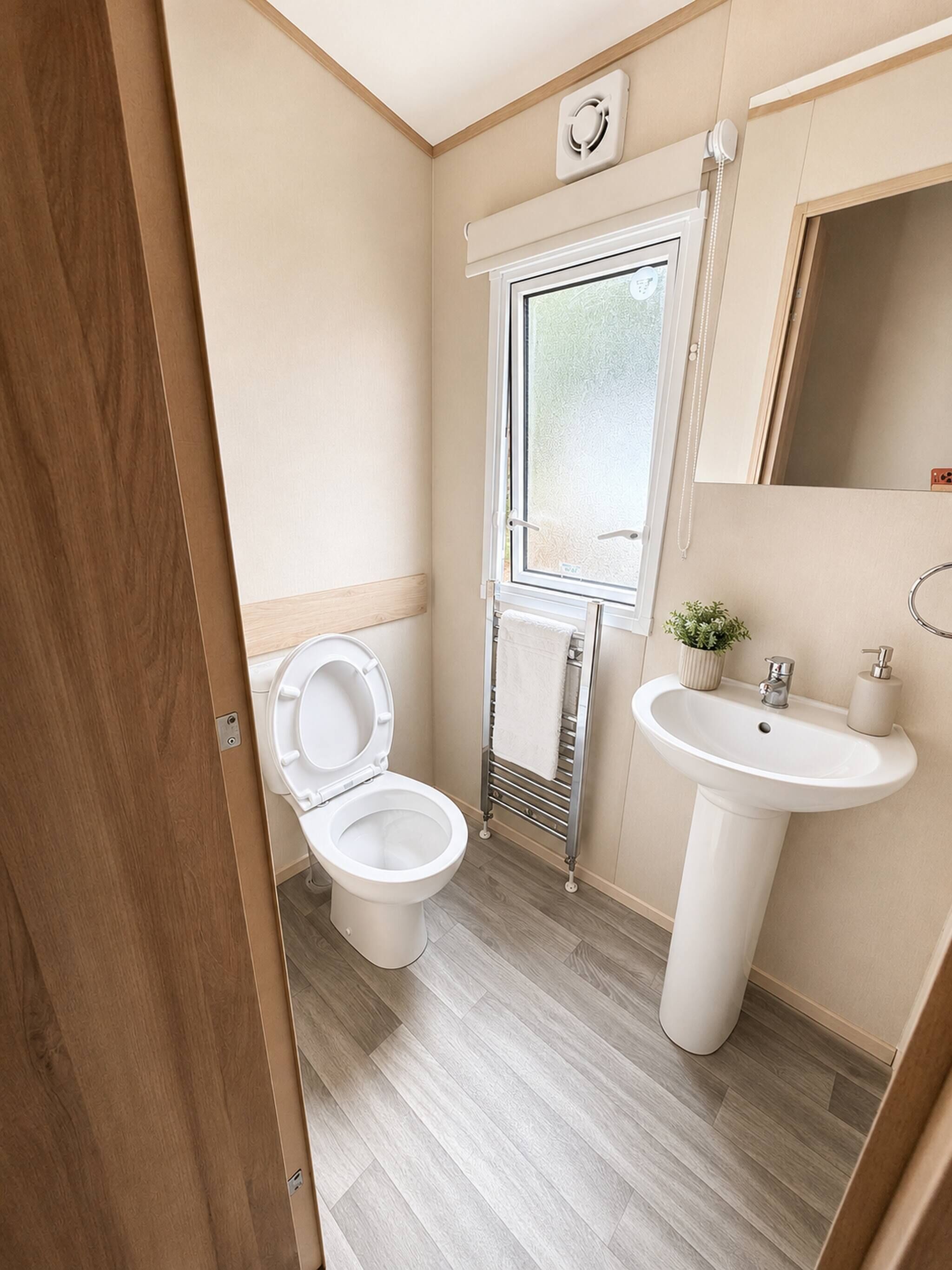 Ein kleines Badezimmer mit Toilette, Waschbecken und Fenster.