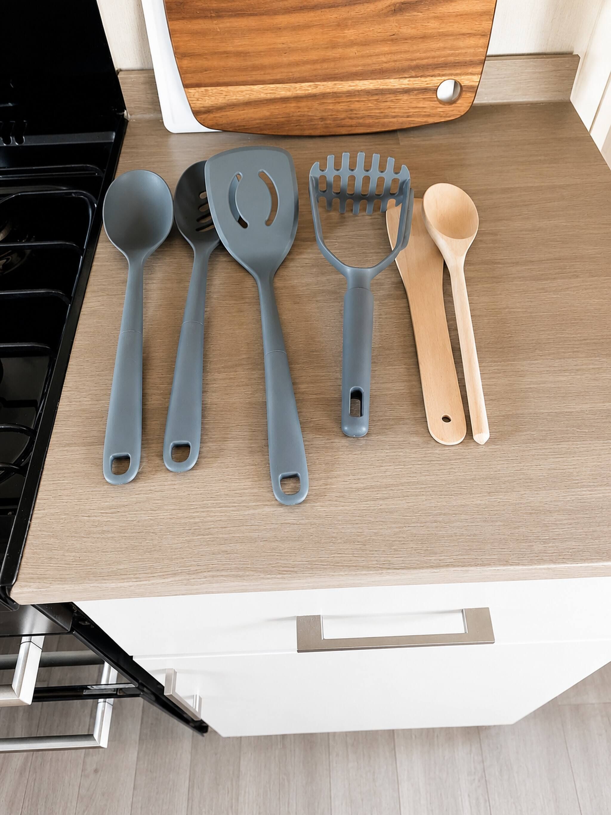 A kitchen counter with various utensils including a spatula, a spoon, and a spatula holder.