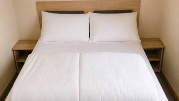 A neatly made bed with a quilted mattress, wooden headboard, and two bedside tables with lamps.