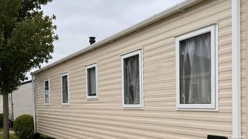 A row of mobile homes with a grassy lawn and a paved walkway.