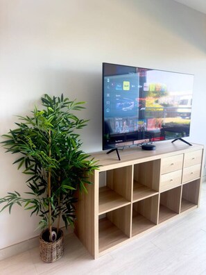 Ein Fernseher auf einem Holzständer, neben ihm eine Bambuspflanze.