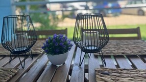 Una mesa de madera con dos candelabros de alambre y una planta en maceta con flores moradas.