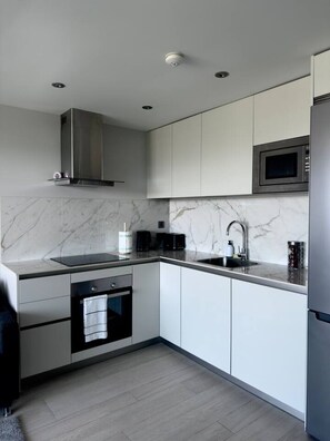 Een moderne keuken met een ingebouwde oven, magnetron en een rvs afzuigkap.
