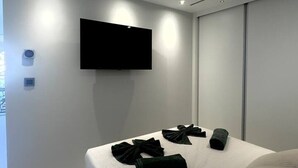 Un dormitorio moderno con una cama, un televisor de pantalla plana montado en la pared y un armario con puertas correderas.