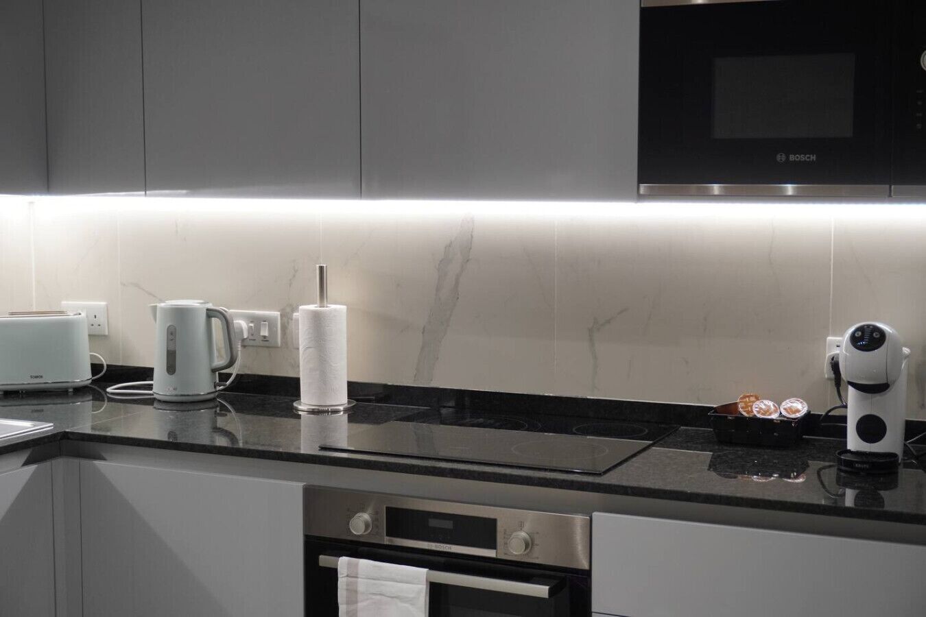 A modern kitchen with a built-in microwave, a kettle, and a toaster on the counter.