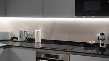 A modern kitchen with a built-in microwave, a kettle, and a toaster on the counter.
