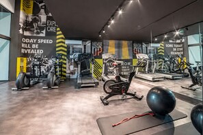 Ein modernes Fitnessstudio mit diversen Trainingsgeräten, motivierenden Postern und einem sauberen, gut beleuchteten Innenraum.