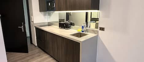 Cocina moderna con armarios de madera oscura, un lavamanos de acero inoxidable y un microondas integrado.