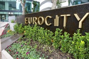A sign with the words 'EUROCITY' in large letters, surrounded by a landscaped garden with various plants and flowers. - Skyline Studio EuroCity | Pool & Gym | City Centre (Gibraltar)