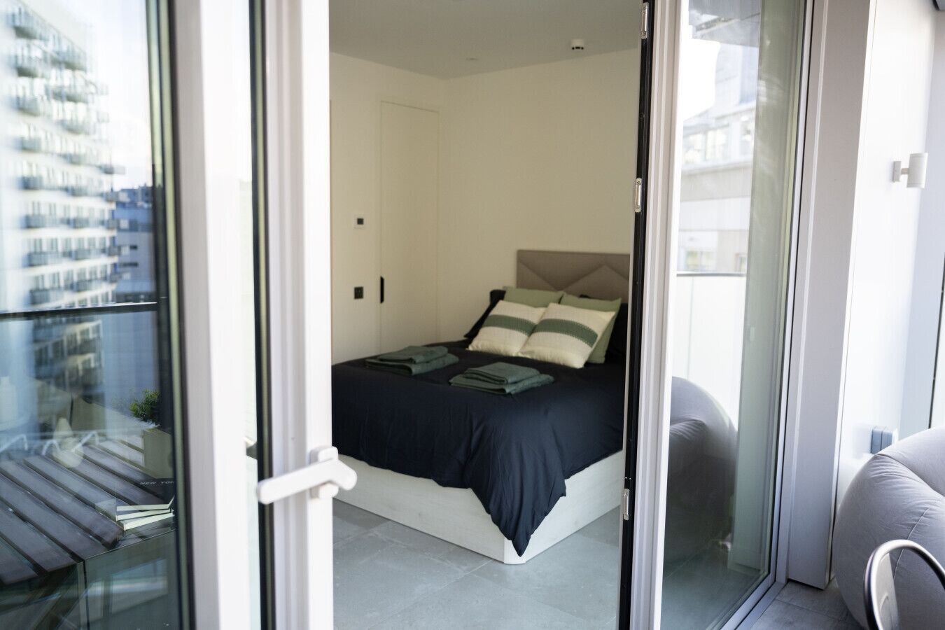 A modern bedroom with a bed, pillows, and a bedside table.