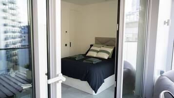 A modern bedroom with a bed, pillows, and a bedside table.