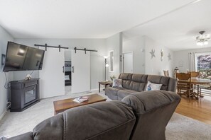 A modern living room with a sofa, coffee table, and a flat-screen TV mounted on the wall. - Palisade Paradise | Quiet escape with Hot tub (Rockaway Beach)