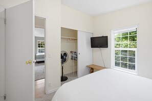A bedroom with a bed, a TV mounted on the wall, a window, and a door leading to another room. - Palisade Paradise | Quiet escape with Hot tub (Rockaway Beach)