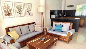 Sala de estar com sofá, poltrona, mesa de centro e uma obra de arte na parede.