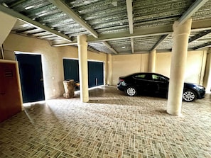 A covered parking area with a car, columns, and a door. - Ocean View Apt 1 Block to Beach and Marina (Cruz de Huanacaxtle)