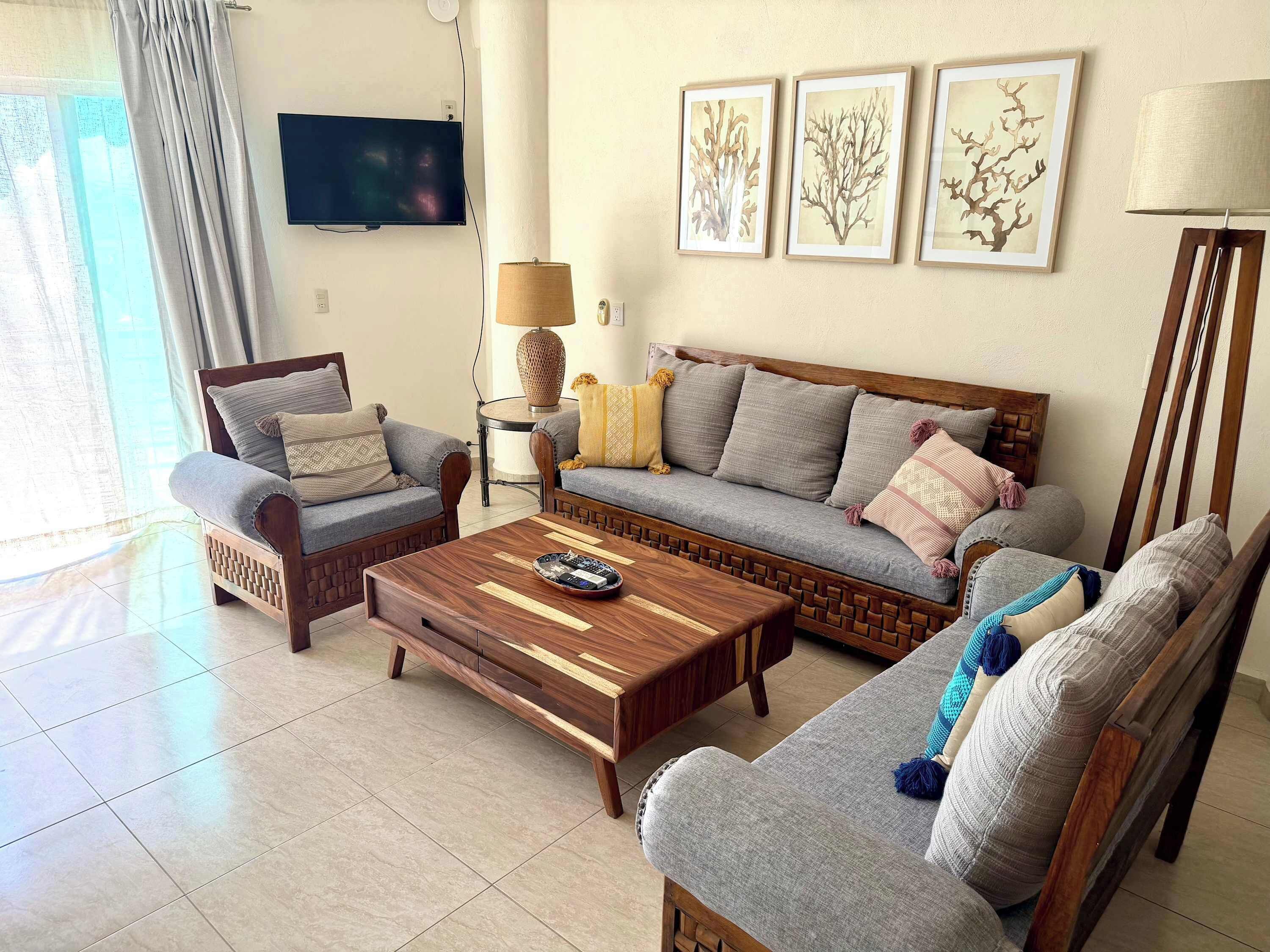 A living room with a sofa, two armchairs, a coffee table, a TV, and wall art.