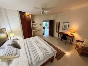 A hotel room with a bed, a desk, a chair, a wardrobe, and a ceiling fan. - Rooftop Patio, Marina Views––1 Block to Beach (La Cruz de Huanacaxtle)