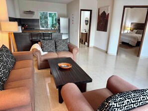 A living room with a sofa, a coffee table, and a kitchen in the background. - Rooftop Patio, Marina Views––1 Block to Beach (La Cruz de Huanacaxtle)