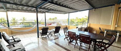 A covered outdoor seating area with a view of palm trees and a cityscape.