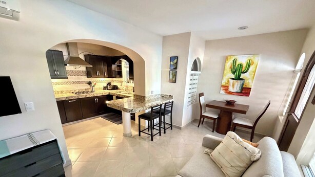 Uma sala de estar moderna com sofá, mesa de centro e área de jantar com cadeiras.