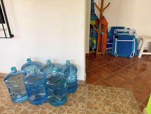 Ein Zimmer mit Fliesenboden, einer weißen Wand und einem hölzernen Kleiderständer mit gefalteter Kleidung.