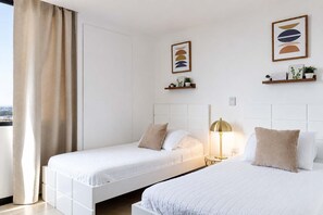 Une chambre d’hôtel avec deux lits, une lampe de chevet et des œuvres d’art accrochées aux murs.