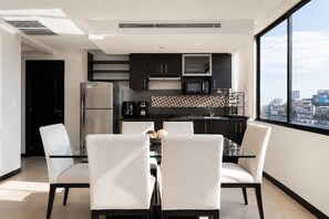 A modern kitchen with a dining area, large windows, and a city view. - Urban Oasis | Modern Luxury Apartment | Bellini (Guayaquil)