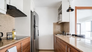 Een moderne keuken met houten kastjes, een roestvrijstalen koelkast en een granieten aanrecht.