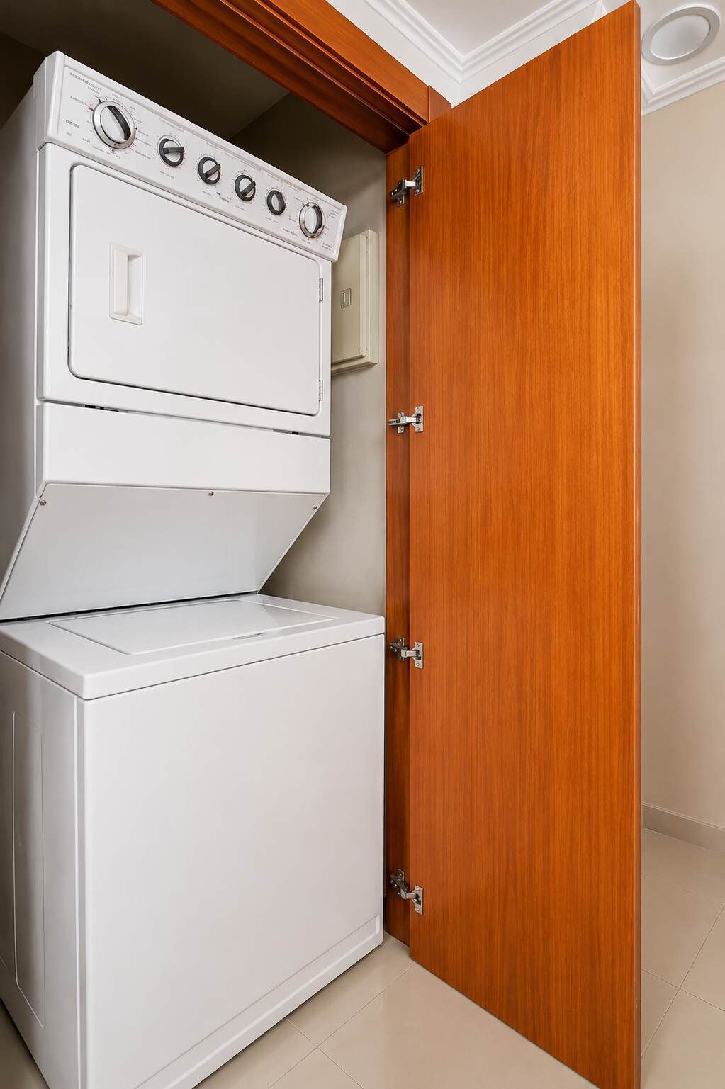A white washer and dryer unit installed in a wooden cabinet with a door.