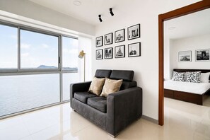 Una sala de estar moderna con un ventanal grande, un sofá, una cama y una pared decorada con marcos.