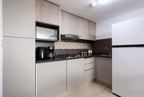 Una cocina moderna con microondas, cafetera y salpicadero de azulejos.