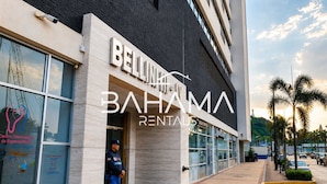 Un edificio moderno con un letrero que dice 'BELLINHA BAHAMA RENTALS' y un guardia de seguridad de pie en la entrada.