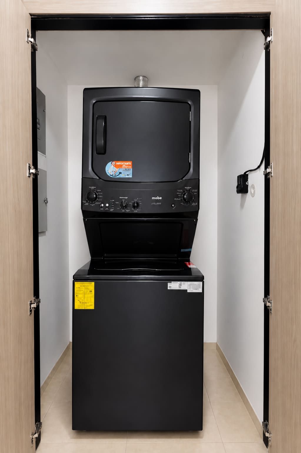 A compact washer and dryer unit with a control panel, placed in a corner with a door frame.