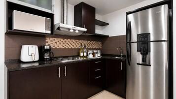 A modern kitchen with stainless steel appliances, a microwave, a coffee maker, and a water dispenser.