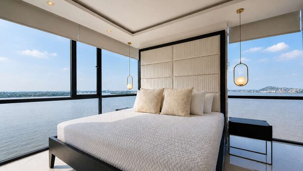 Ein modernes Schlafzimmer mit einem großen Bett, Blick auf das Wasser und die Stadt.