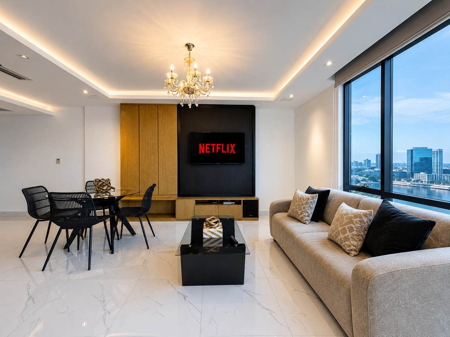A modern living room with a flat-screen TV, a chandelier, a sofa, and a dining area with chairs.