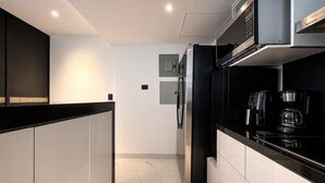 Eine moderne Küche mit integriertem Mikrowellenherd, Kühlschrank und Kaffeemaschine.