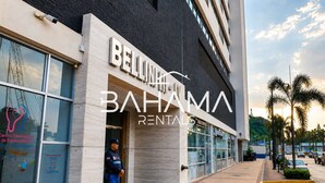 Un bâtiment moderne, sur lequel on peut lire l’inscription « BELLINHA BAHAMA RENTALS », et un agent de sécurité qui se tient à l’entrée.