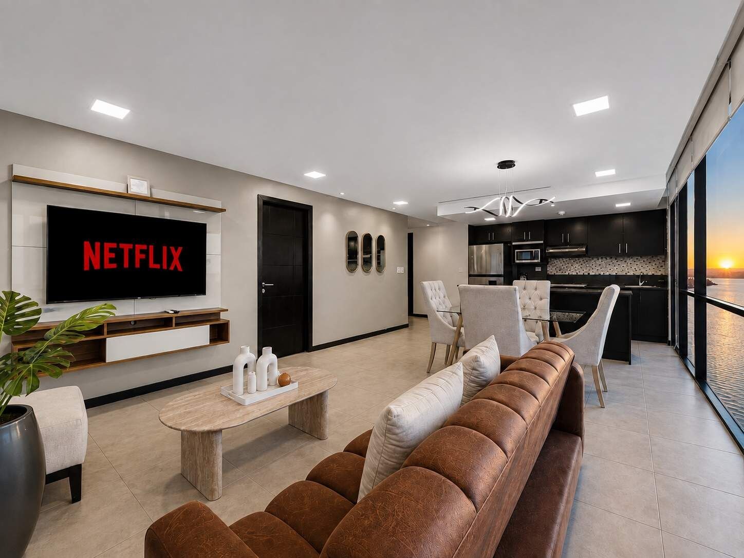 Ein modernes Wohnzimmer mit Flachbildfernseher, einer Couch, einem Couchtisch und einem Essbereich mit Stühlen.