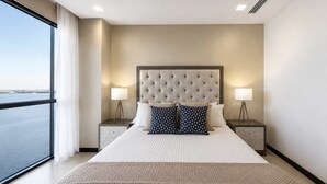 Habitación de hotel con una cama grande, dos mesitas de noche y vista al agua.