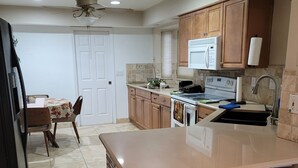 A kitchen with a central island, wooden cabinets, a microwave, and a sink. - Marvelous 3-bedroom house with AC big Pool and Jaccuzi very quiet in Lehigh Acre (Lehigh Acres)