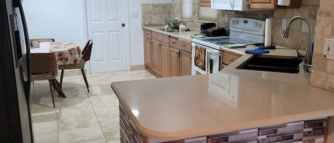 A kitchen with a central island, wooden cabinets, a microwave, and a sink.
