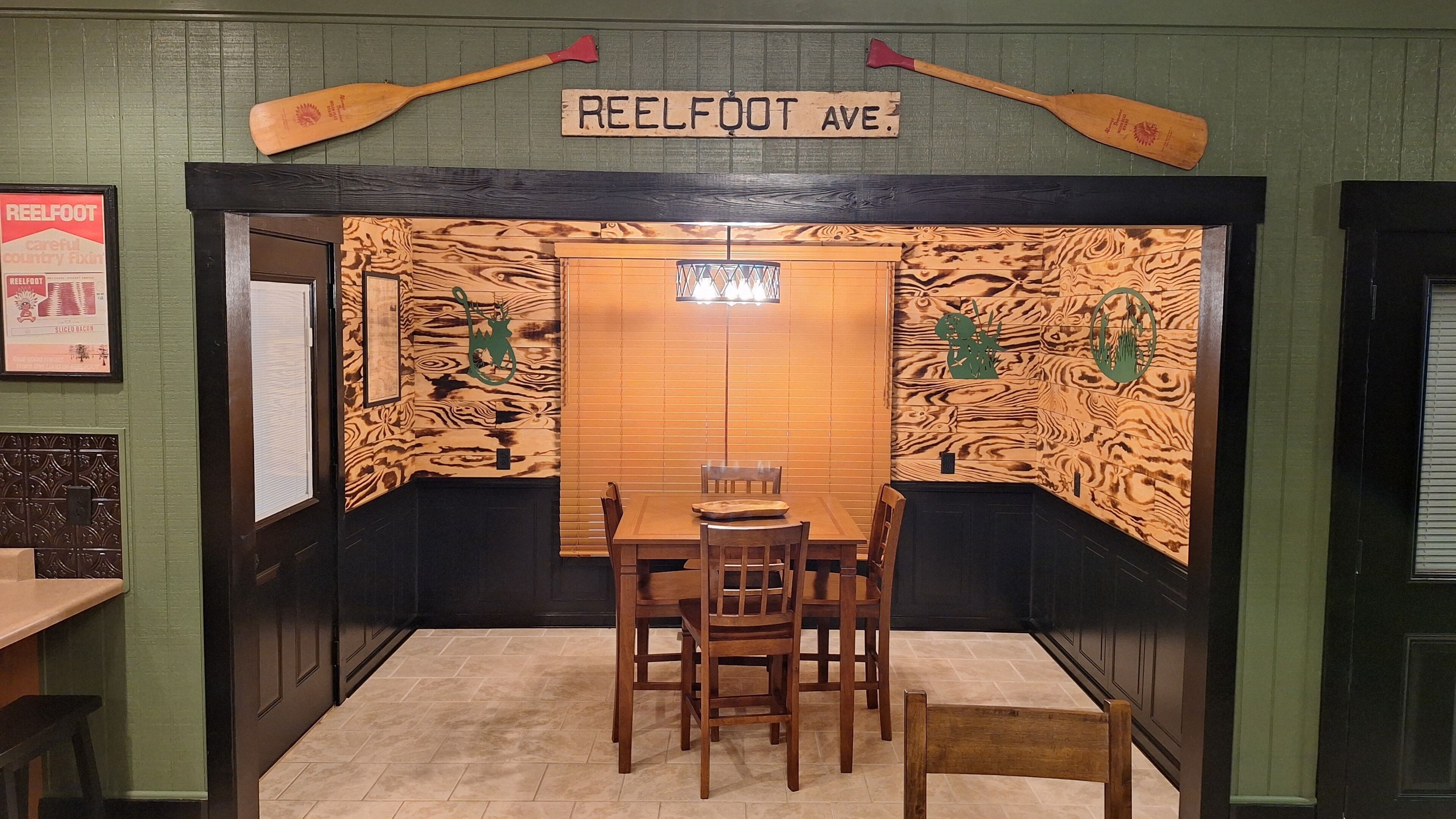 Interior de un restaurante con un diseño de pared de madera, un letrero que dice 'REELFOOT AVE.' y una mesa con sillas.