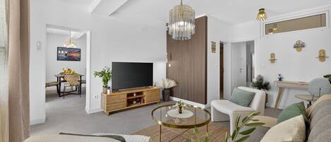 A modern living room with a flat-screen TV, a round coffee table, and a sofa.