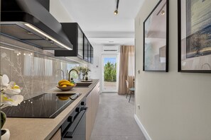 A modern kitchen with a central island, built-in oven, and a view to the outdoors. - Two Bedroom Apartment with Terrace (Mlini)